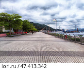 Lantau Island, Hong Kong - April 09, 2024: Scenic waterfront promenade in Lantau Island, Hong Kong, adorned with greenery and cloudy skies. Редакционное фото, фотограф Кривошеина Елена Леонидовна / Фотобанк Лори