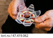 Elderly person organizing medication in weekly pill organizer at home during daytime. Стоковое фото, фотограф Вербицкая Светлана / Фотобанк Лори
