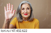 A graceful elderly woman confidently looks at the camera, resting her hands, dressed in a casual yellow t-shirt, posing indoors. Стоковое AI-видео, аниматор Ирина Старикова / Фотобанк Лори