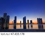 Sharjah, UAE - March 3, 2025: Cityscape with buildings under construction at sunset seen from Al Khan Corniche waterfront. Редакционное фото, фотограф Оксана Чаюн / Фотобанк Лори