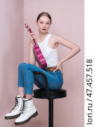 Musician with ukulele in hand sits on bar stool with both legs thrown over its back, looking camera. Стоковое фото, фотограф А. А. Пирагис / Фотобанк Лори