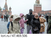 Иностранные туристы гуляют по Красной площади в центре города Москвы во время холодной, ветряной погоды, Россия. Редакционное фото, фотограф Николай Винокуров / Фотобанк Лори