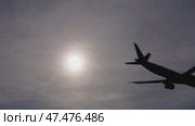 Airliner silhouette landing during bright daytime, sunlight creating dramatic backlighting effect with soft glowing sky background. Стоковое видео, видеограф Данил Руденко / Фотобанк Лори