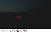The twilight scene captures cars on a dark road, their headlights illuminating the path ahead. The colors merge with the deep blue of sky, signaling onset of twilight. View from a car in motion. Стоковое видео, видеограф Воловодов Владимир / Фотобанк Лори