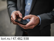 Closeup of male hands using smart phone, blurred trendy background. Man in business suit use mobile phone. Day light. Unrecognizable person touching smartphone screen. Businessman holding cellphone. Стоковое AI-изображение, AI-художник Марина Демидюк / Фотобанк Лори