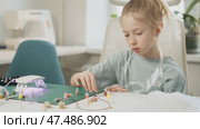 Child refines motor skills by picking up small decorations for resin jewelry. Precision and patience required for detailed work help develop dexterity and artistic sense. Chooses bottle of glitter. Стоковое видео, видеограф Енваев Андрей / Фотобанк Лори