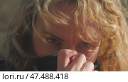 Close-up of a girl's face covered by a snood. Her long wavy hair, subtly illuminated by the sunlight, is fluttering in the wind. Her gaze is directed at the camera. Стоковое видео, видеограф Воловодов Владимир / Фотобанк Лори