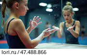 Girl is in a gymnasium, cleaning her hands with powder. Стоковое AI-изображение, AI-художник Sergey Grishin / Фотобанк Лори