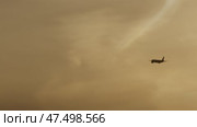 Commercial jet airplane gaining altitude during golden hour sunset, disappearing into hazy atmospheric sky with contrail stretching behind distant aircraft. Стоковое видео, видеограф Данил Руденко / Фотобанк Лори
