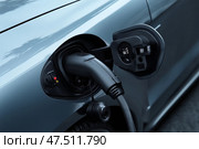 Charging an electric vehicle at a station during the day in a modern city. Зарядка электромобиля на станции в дневное время в современном городе. Стоковое AI-изображение, AI-художник Katsiaryna Repich / Фотобанк Лори