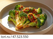 Roasted broccoli steaks artfully arranged on a minimalist plate. Accentuated by tomato butter and tapenade, this dish exemplifies elegant vegan cuisine with gourmet finesse. Стоковое AI-изображение, AI-художник Nart / Фотобанк Лори