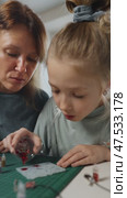 Popular trend epoxy resin jewelry making at home. Mom and girl enthusiastically pour epoxy resin mixed with red glitter into tiny mold to make jewelry, bringing their creative vision to life. Стоковое видео, видеограф Енваев Андрей / Фотобанк Лори