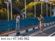 The bridge over the Kotorosl River to Damansky Island and people passing by. Yaroslavl, Russia. Редакционное фото, фотограф Photojuli / Фотобанк Лори