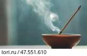 Incense stick burning in a ceramic holder with smoke wafting upwards in a serene setting. Стоковое AI-изображение, AI-художник Сергей Толмачёв / Фотобанк Лори