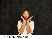 Excitement Fills the Room as a Teenage Girl Expresses Surprise Against a Dark Backdrop. Стоковое фото, фотограф Aleksandr Golubev / Фотобанк Лори
