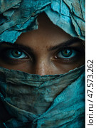 A person wrapped in tattered blue fabric showcases captivating green eyes, creating an aura of mystery and intrigue in the atmosphere. Стоковое AI-изображение, AI-художник Данила Большаков / Фотобанк Лори
