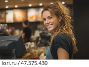 Smiling cashier assists customers in busy retail store while colleagues work. Улыбчивый кассир обслуживает покупателей в оживленном розничном магазине, пока коллеги работают. Стоковое AI-изображение, AI-художник Katsiaryna Repich / Фотобанк Лори