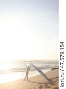 A person is standing on a sandy beach while holding a surfboard. Стоковое фото, фотограф Женя Канашкин / Фотобанк Лори