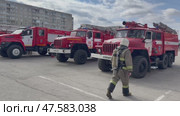 ANGARSK, IRKUTSK REGION, RUSSIA - April 08, 2025: Video of a team of firefighters returning to their trucks after extinguishing a building. Red fire trucks are lined up on the square. Preventive training. Редакционное видео, видеограф Виктория Катьянова / Фотобанк Лори