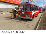 ANGARSK, IRKUTSK REGION, RUSSIA - April 08, 2025: Preventive training on extinguishing fire in shopping center. Squad of firefighters in special clothing, helmets, with oxygen cylinders arrived in red bus. Редакционное фото, фотограф Виктория Катьянова / Фотобанк Лори