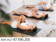 Three generations of women do preparatory stretching, lying on back and benting one leg at knee. Стоковое фото, фотограф Яков Филимонов / Фотобанк Лори