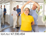 Senior man dancing bachata with female partner during group class. Стоковое фото, фотограф Яков Филимонов / Фотобанк Лори