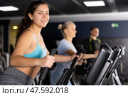 Girl warming up on elliptical machine before training in gym. Стоковое фото, фотограф Яков Филимонов / Фотобанк Лори