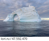 A huge high breakaway glacier drifts in the southern ocean off the coast of Antarctica at sunset, the Antarctic Peninsula, the Southern Arctic Circle, azure water, cloudy weather. Стоковое фото, фотограф Vladimir Drozdin / Фотобанк Лори
