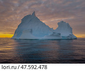 A huge high breakaway glacier drifts in the southern ocean off the coast of Antarctica at sunset, the Antarctic Peninsula, the Southern Arctic Circle, azure water, cloudy weather. Стоковое фото, фотограф Vladimir Drozdin / Фотобанк Лори