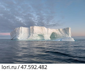 A huge high breakaway glacier drifts in the southern ocean off the coast of Antarctica at sunset, the Antarctic Peninsula, the Southern Arctic Circle, azure water, cloudy weather. Стоковое фото, фотограф Vladimir Drozdin / Фотобанк Лори