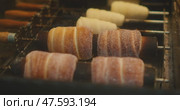 Traditional chimney cakes are being grilled over open flames at a street market in Prague, covered in sugar and cinnamon. Стоковое видео, видеограф Igor Tichonow / Фотобанк Лори