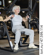 Elderly woman training on chest press machine in gym. Стоковое фото, фотограф Яков Филимонов / Фотобанк Лори