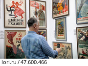Посетитель фотографирует на телефон выставку советского плаката времен Великой Отечественной войны 1941-1945 года на международной ярмарке интеллектуальной литературы Non/fiction в Гостином дворе города Москвы, Россия. Редакционное фото, фотограф Николай Винокуров / Фотобанк Лори