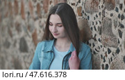 Portrait of a long-haired girl in a denim jacket against a stone wall. Стоковое видео, видеограф Mikhail Davidovich / Фотобанк Лори