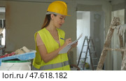 Woman foreman in a protective helmet and yellow vest checks the completed construction work on the drawing. Стоковое видео, видеограф Яков Филимонов / Фотобанк Лори