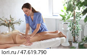 Focused professional young masseuse performing anti-cellulite thigh and bum massage to adult female client in spa center. Стоковое видео, видеограф Яков Филимонов / Фотобанк Лори