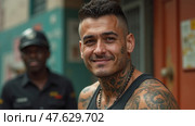 A Smiling Man With Intricate Tattoos Stands Outdoors, Engaging Directly With the Camera. Стоковое AI-изображение, AI-художник Sergey Grishin / Фотобанк Лори