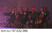 A classical music ensemble performs under soft lighting, showcasing musicians poised with violins and a cello. The stage atmosphere exudes elegance and professionalism. Russia, January 1, 2025. Редакционное видео, видеограф Воловодов Владимир / Фотобанк Лори