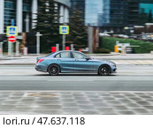 Side view rolling shot with blue Mercedes-Benz C class car in motion. Mercedes AMG C 43 is driving along the street in city with blurred autumn background. Редакционное фото, фотограф Константин Григорьев / Фотобанк Лори
