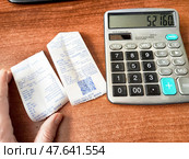 Kirov, Russia - March 12, 2025: Calculating expenses with receipts and a calculator on a wooden desk in a bright workspace. Редакционное фото, фотограф Кривошеина Елена Леонидовна / Фотобанк Лори