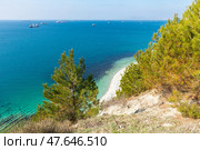 Геленджик. Panoramic view of the wild narrow beach Blue Abyss in Gelendzhik, Russia under a steep white cliff overgrown with mountain pines with amazing turquoise water and surf wave near the shore. Стоковое фото, фотограф Ирина Михайличенко / Фотобанк Лори