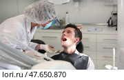 Girl doctor dentist in white coat examines oral cavity of male patient in dentistry. Стоковое видео, видеограф Яков Филимонов / Фотобанк Лори