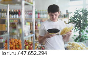 Casually dressed young guy examining two chip bags while shopping for snacks in local grocery store, comparing ingredients and nutritious value before buying. Стоковое видео, видеограф Яков Филимонов / Фотобанк Лори
