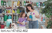 Woman with child family selects and studies label liquid detergent and tile cleaner spray. Стоковое видео, видеограф Яков Филимонов / Фотобанк Лори