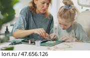 Mother guiding daughter in crafting resin jewelry, placing beads into mold. Shared hobby strengthens relationship and promotes collaborative learning. Handmade epoxy arts workshop, DIY masterclass. Стоковое видео, видеограф Енваев Андрей / Фотобанк Лори