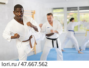 Middle-aged man attendee of karate classes fighting with his opponent in sports hall. Стоковое фото, фотограф Яков Филимонов / Фотобанк Лори