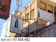 Manama, Bahrain - Jan 08 2024, panoramic view of facades of buildings with signages with inscriptions in Arabic on a narrow street, at daytime with a clear blue sky, without people, Manama, Bahrain. Редакционное фото, фотограф Сергей Богомяко / Фотобанк Лори