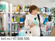 Store visitor woman purchases in household chemicals department, choose multisurface cleaner spray. Стоковое фото, фотограф Яков Филимонов / Фотобанк Лори