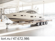 Large motor yacht being transported on a trailer inside a boat storage facility. Стоковое AI-изображение, AI-художник Юрий Поздников / Фотобанк Лори