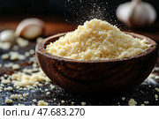 Close-up of grated parmesan cheese in a wooden bowl against a dark background. The cheese crumbles appetizingly, creating the effect of movement and freshness. Individual crumbs and garlic cloves are visible in the frame, which emphasizes the culinary atmosphere. A perfect image for recipes, food blogs, restaurant menus or product packaging. Стоковое AI-изображение, AI-художник Анна Кривицкая / Фотобанк Лори